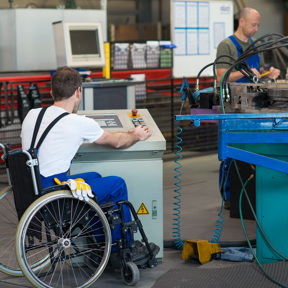 disabled worker in wheelchair in factory on the machine